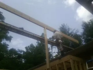 Carpenter setting a ridge beam over a new addition frame — Ice Dam Removal by Roofing Brothers in Blooming Grove
