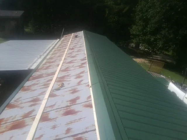 Old rusted panels beside newly installed green metal roofing — Wind Damage Roof Repair by Roofing Brothers in Blooming Grove