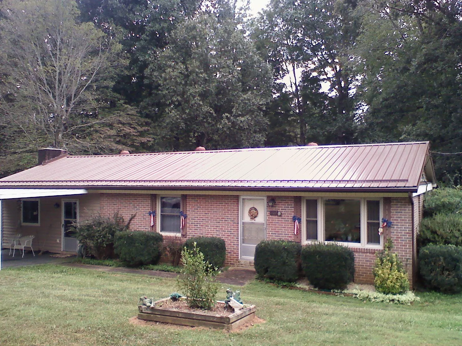 Bronze metal roof on a brick ranch home with a carport in Blooming Grove