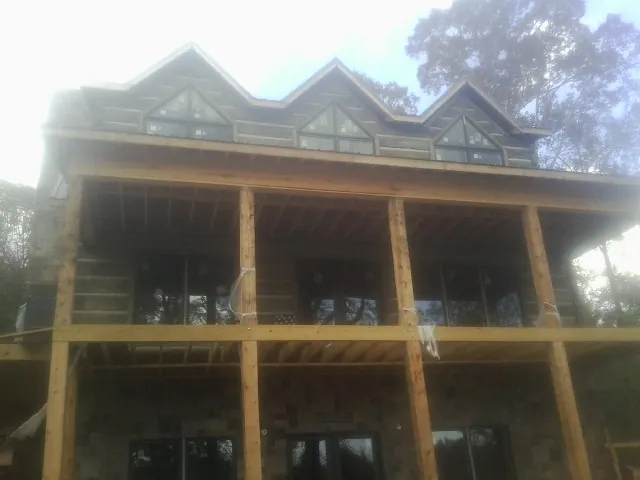 Dormers and porch framing on a large log home under construction — Roof Coating work by our crew in Blooming Grove