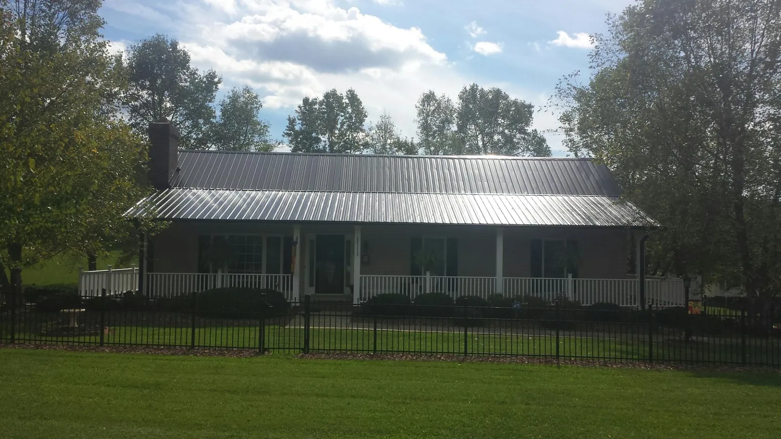 Gray metal roof on a brick ranch with a full width front porch — Gutter Guard Installation work by our crew in Blooming Grove