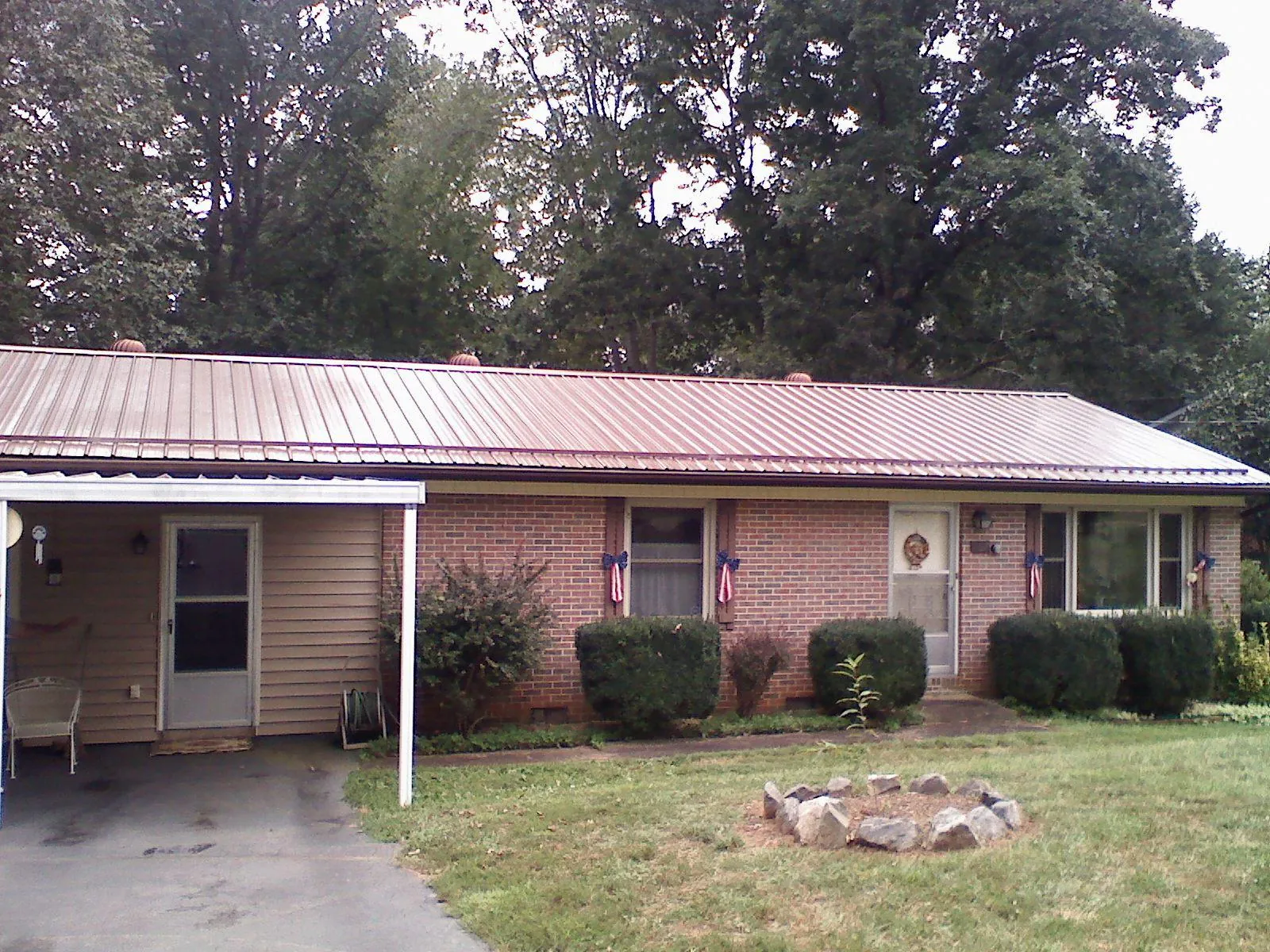 Bronze metal roof and carport on a brick ranch home — Roof Repair work by our crew in Blooming Grove