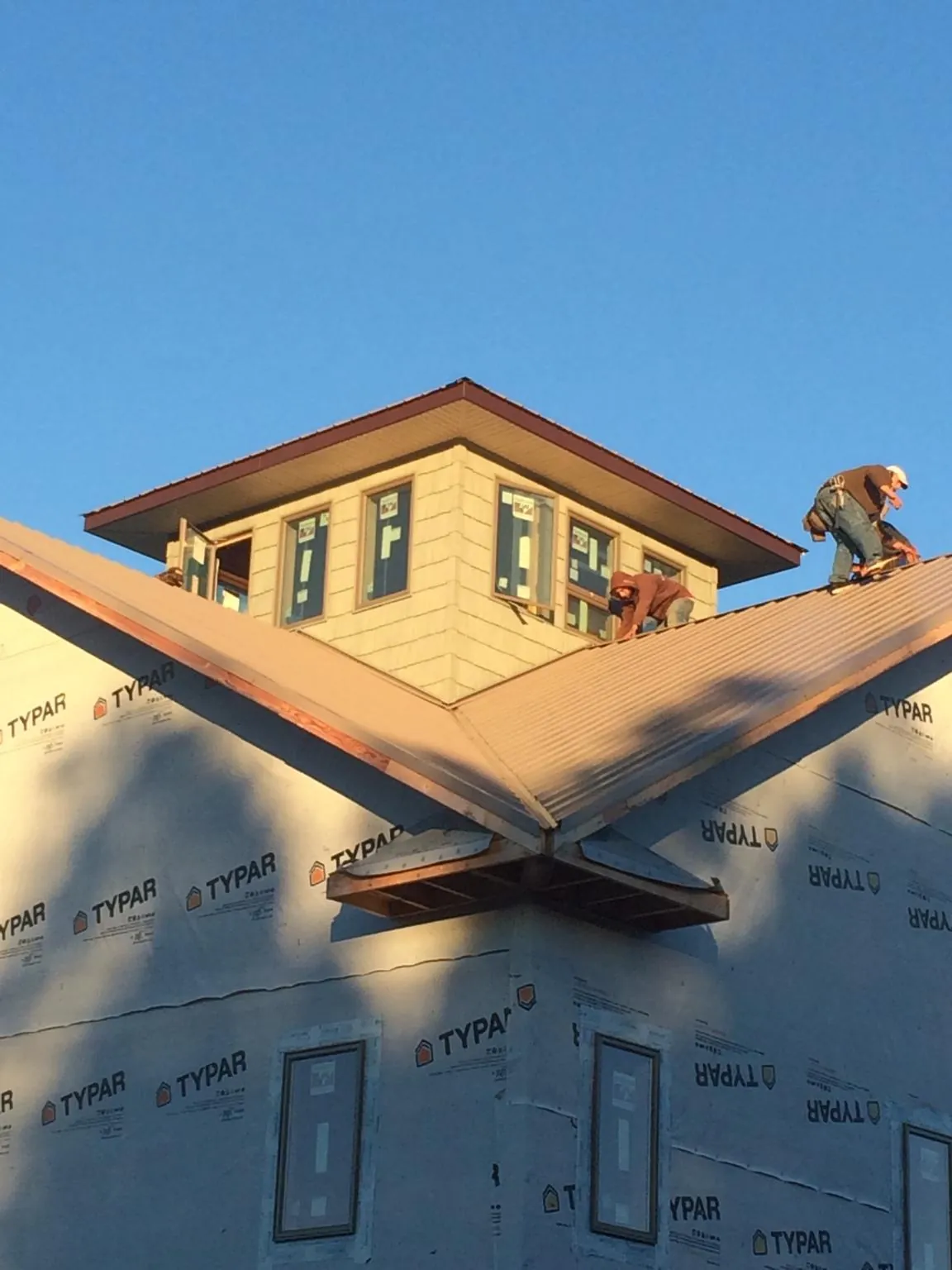 Roofers working around a rooftop cupola on a new metal roof at sunset — Roof Waterproofing in Blooming Grove by Roofing Brothers